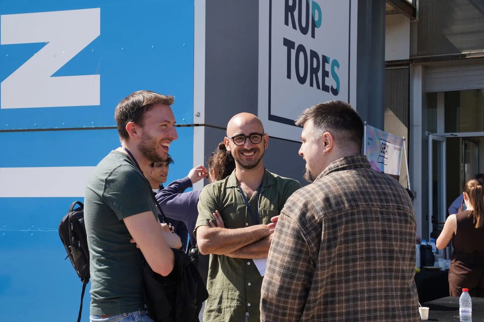 Tres asistentes del Gen AI Summit EU 2026 conversando en el exterior del venue